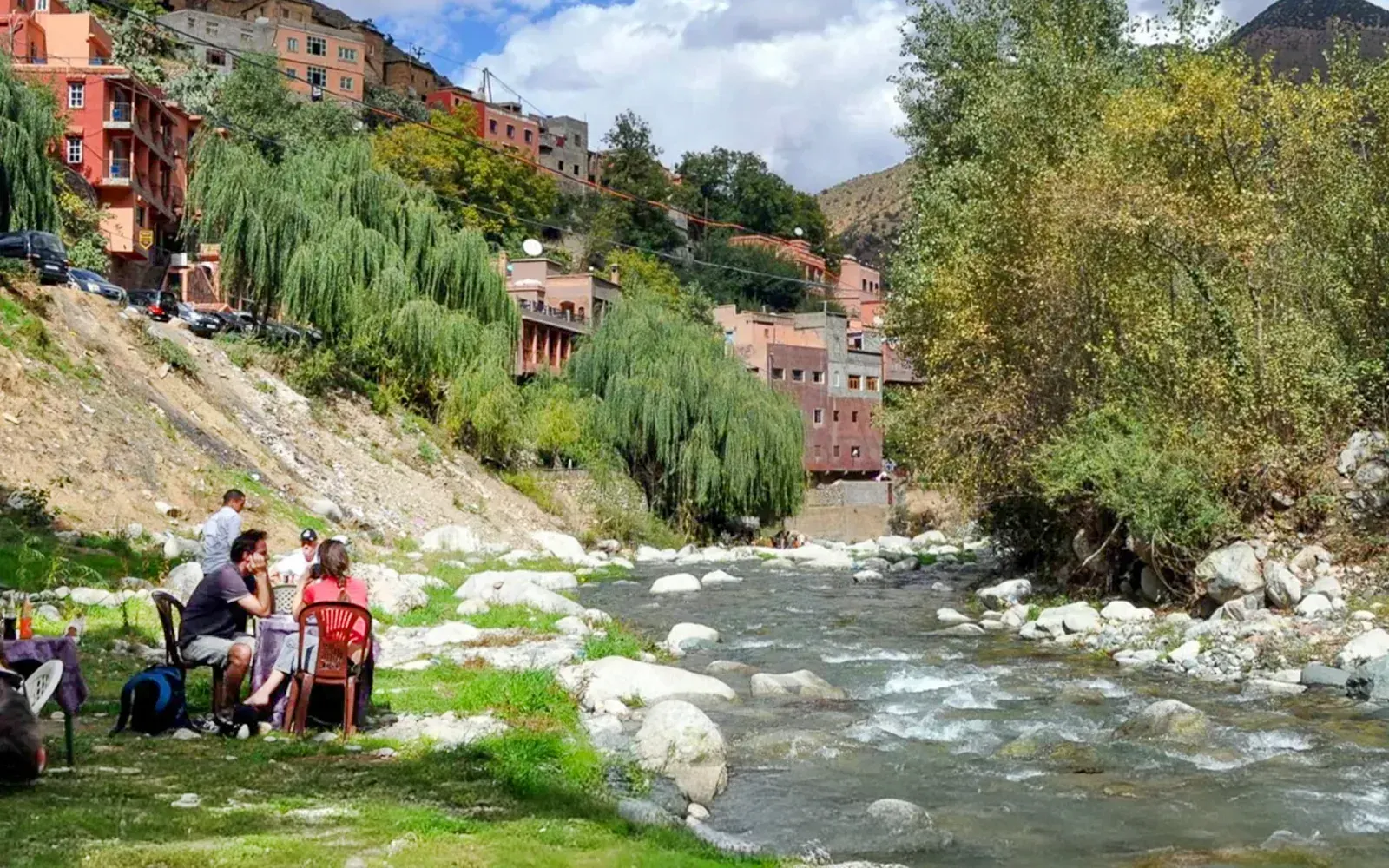 People sitting on the grass beside the river in the Ourika Valley