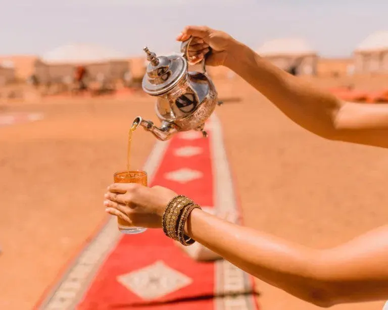Tea being poured into a glass in the desert